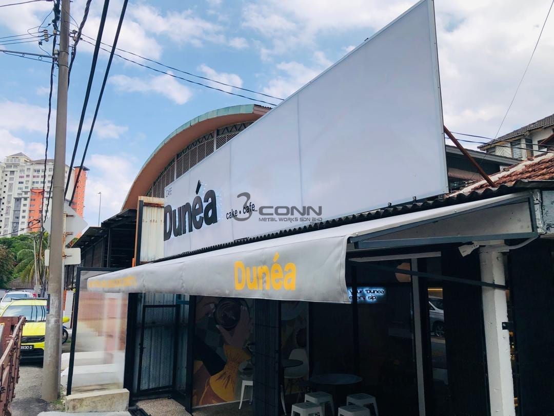 A curved fixed canopy over a café shopfront, seen from the street.