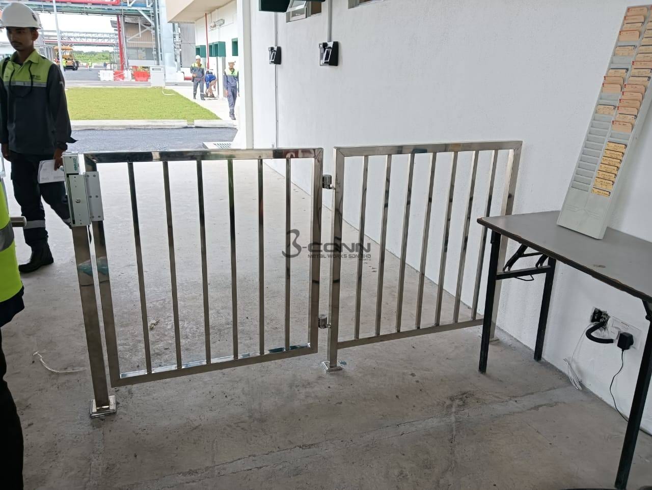 A stainless steel railing with a matching gate section at the edge of a raised floor, on a building site.